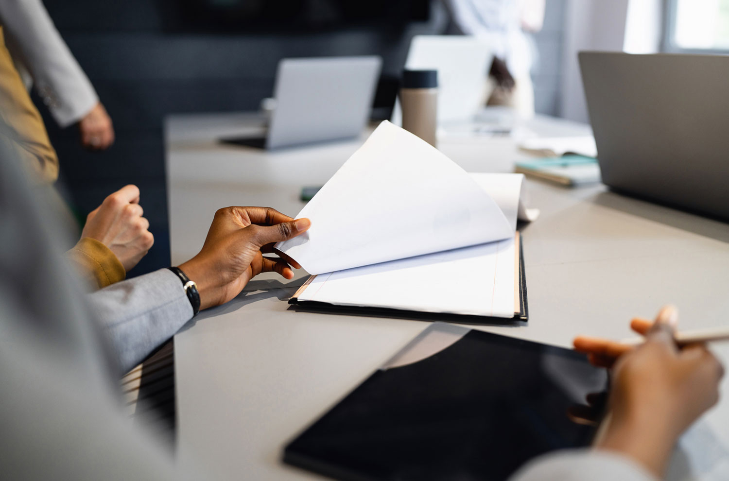 Male hand flipping through stack of paperwork on clipboard