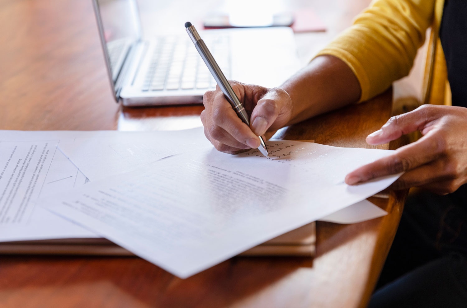 Female hands signing paperwork on wooden desk