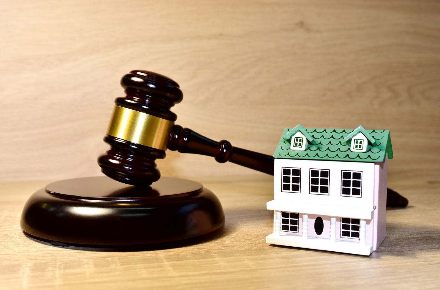 Gavel with model house sitting on a desk