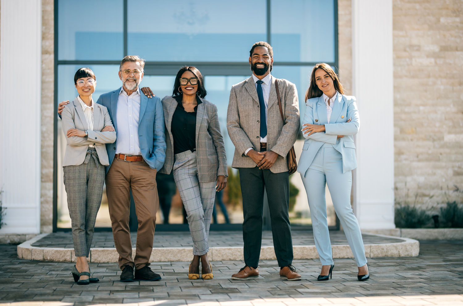Five businesspeople standing together in front of building