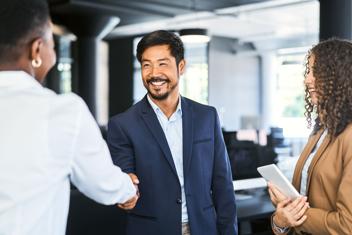 Businessman shaking hands with businesswoman inside a real estate office.