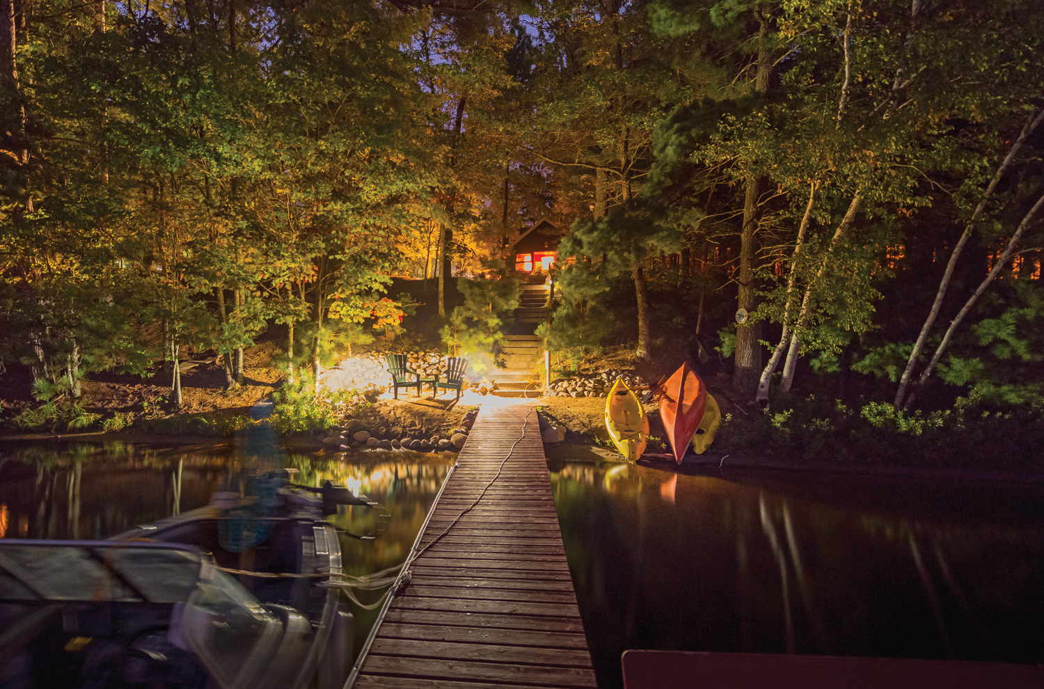 Nightlights along lake dock with stairs leading up to lakehouse
