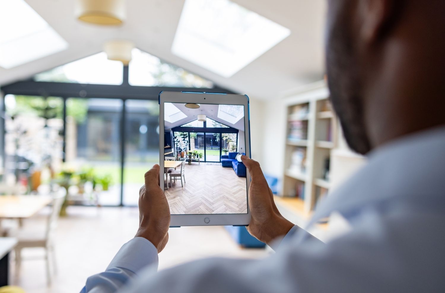 Male real estate agent taking photos inside living room with tablet 