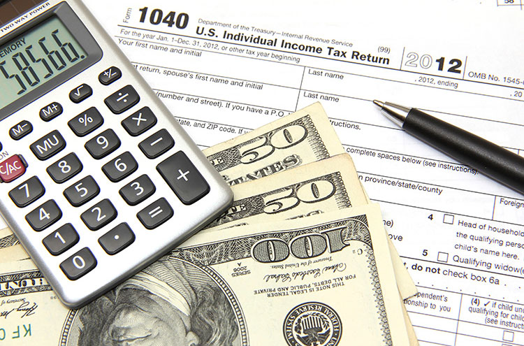 Tax forms, dollar bills and calculator on desk